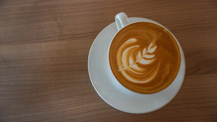 latte art in a white cup, on a wooden table