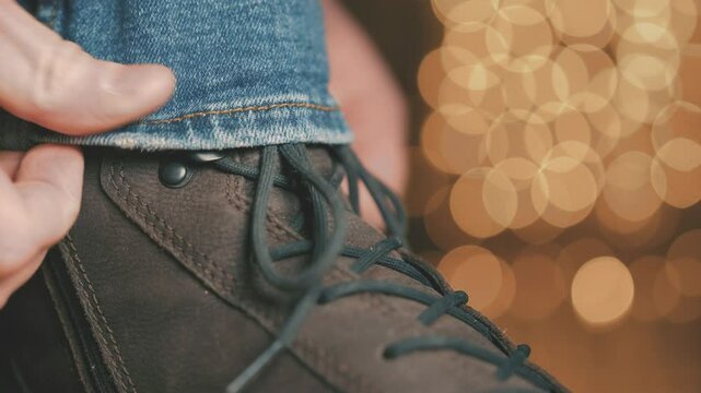 Adjusting Jeans over Winter Boot, Man Fixing Denim over Footwear for Cold Weather Protection, Casual Boot with Golden Bokeh