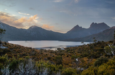 Serene dawn at Dove Lake with Cradle Mountain peaks, tranquil reflections, and misty clouds in Tasmania, Australia