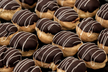 Rows of chocolate-glazed pastries with icing.