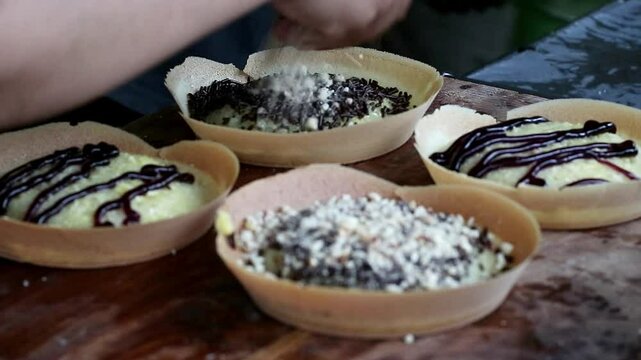Asian Indonesia man's hand cooking street food terang bulan with nuts, chocolate, cheese, milk. entrepreneurship idea. empowerment concept. Popular pancake sweet street food  in Indonesia. 