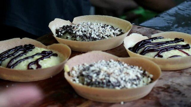 Asian Indonesia man's hand cooking street food terang bulan with nuts, chocolate, cheese, milk. entrepreneurship idea. empowerment concept. Popular pancake sweet street food  in Indonesia. 