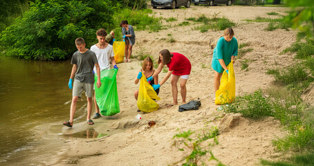 a group of student volunteers clean up trash on the beach