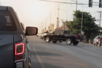 Rear side view of pickup car. Stop and turn on brake light on asphalt road. Stopped at a traffic light and there was a car crossing the road.