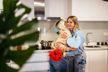 Women embracing and exchanging gifts in the kitchen on valentine's day