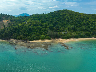 A breathtaking aerial view of a lush green coastline with winding paths, crystal-clear turquoise waters, and distant islands under a partly cloudy sky. Lam Nga is in Silay island Phuket. green sea