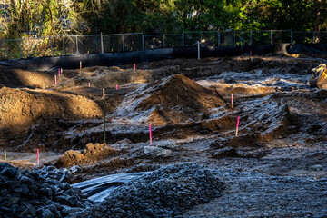 Residential re-development, old house taken down and lot ready for new construction, surveyor stakes and piles of dirt, frosty frozen ground in winter
