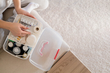 Closeup female hand neatly placing medicament at domestic first aid kit top view.