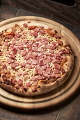 Pizza with ham and mozzarella cheese on wooden background. Soft focus. Close up	