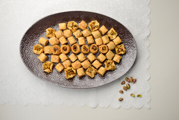 Photo of Baklava, a Middle eastern dessert made of filo pastry, nuts and honey. Authentic Mediterranean sweets served in large plate, view from above.   