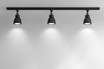 Three black spotlights mounted on a track illuminate a blank wall.