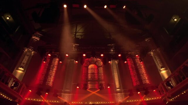 Stunning stained-glass windows and intricate architectural elements at Paradiso Amsterdam glow under dynamic red lighting, blending historical charm with modern performance aesthetics.