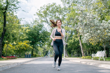 Asian beautiful woman running in a park for health, wellness and outdoor exercise. Nature, sports and female athlete runner doing cardio workout in garden. Healthy Concept.