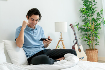 Asian young handsome man gamer play mobile game on smartphone at home