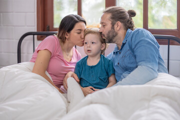 Obraz premium Family enjoying a cozy morning together in bed with warm blankets and natural light
