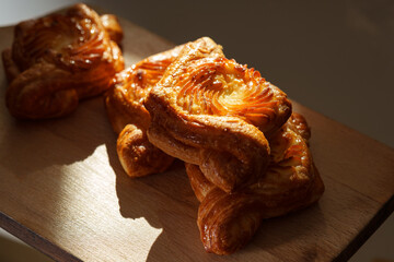 Flaky pastry treats arranged on a wooden board in warm afternoon light