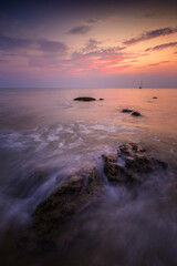 Beautiful landscape of colorful sky and wave crashing rocks on the Long Beach (Phra Ae Beach) in Koh Lanta, Thailand, at sunset. 