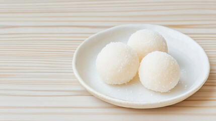 Coconut Balls on Plate: Three delectable coconut balls rest on a simple white plate, placed against a light wood backdrop. The image evokes feelings of sweetness and simple pleasures.
