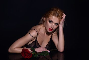 Naklejka premium Seductive woman holding red rose. Slim sexy beautiful woman with naked shoulder hold red roses, isolated on studio background. Portrait of sensual girl with flowers.