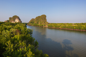 Khao Kanab Nam, the two famous twin limestone mountains, and mangrove forests by the Krabi River in Krabi Town, Thailand, viewed from above on a sunny day.