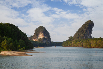 Khao Kanab Nam, the two famous twin limestone mountains, and mangrove forests by the Krabi River in Krabi Town, Thailand on a sunny day. 