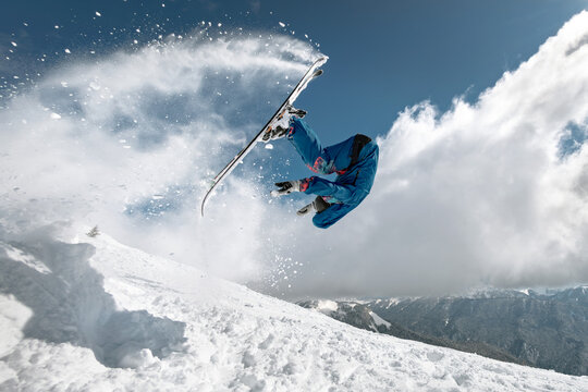 Professional skier jumps at high speed and makes front flip trick at ski resort