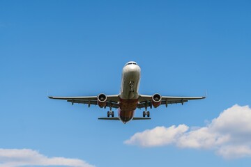 Airplane flying high against a clear blue sky with fluffy clouds during daytime