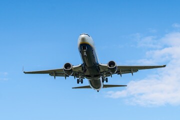 Airliner prepares for landing above a clear blue sky in an urban area during daytime