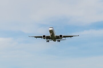 Airplane flying through clear blue skies above a scenic landscape during daylight hours