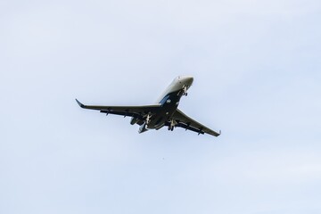 Commercial jet aircraft approaches landing over clear blue sky in mid-afternoon hours at the airport