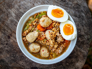 Tom Yum noodles are placed on an old wooden table.