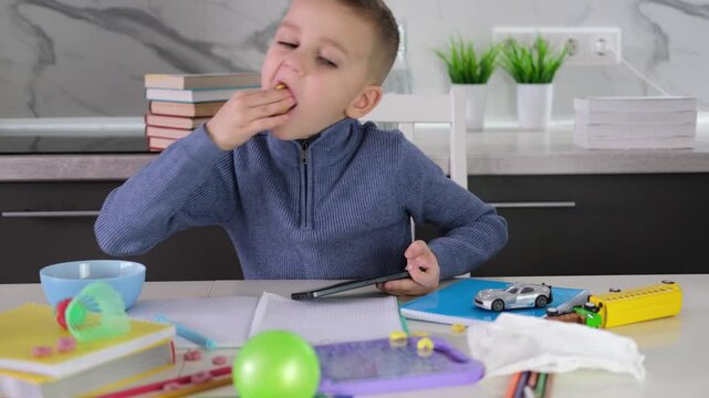 Education, school, learning difficulties, reading difficulties. Child plays with smartphone instead of doing homework. Schoolchild sits at table doing homework among pile of books and scattered toys.