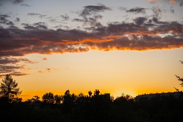 Beautiful sunset over trees and buildings with colorful clouds in the evening sky