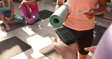 Paying for yoga class, woman holding yoga mat and credit card in studio