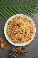 Indian vegetarian pulao or Veg fried rice or Veg Briyabi in brown decorated wooden bowl with isolated. Veg Schezwan Fried Rice ,Vegetarian Szechuan Rice.