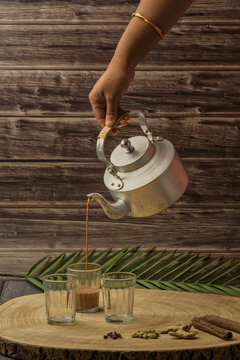 Indian masala chai tea. Masala chai spiced tea with milk and spices or karak chai or cutting chai. Tea being poured into glasses from a kettle