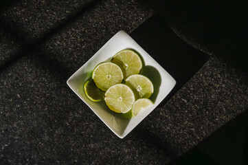 Fresh sliced lime in a bowl in dramatic lighting