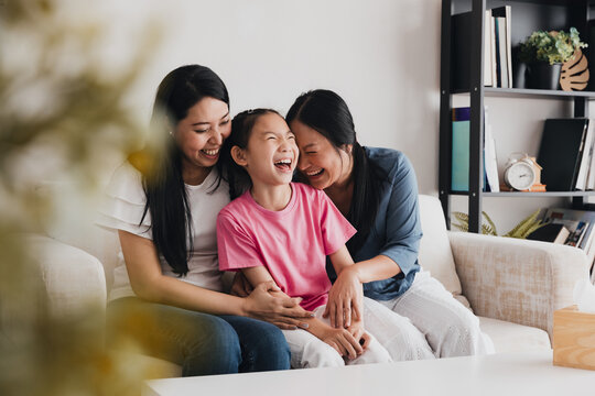 Joyful family moment of LGBTQ couple with their adopted daughter in a cozy living room