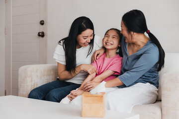 Obraz premium Joyful LGBTQ couple shares a tender moment with their adopted daughter in a cozy living room setting