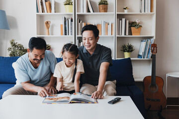 Joyful couple and their daughter enjoy reading together in a cozy living room filled with books and plants