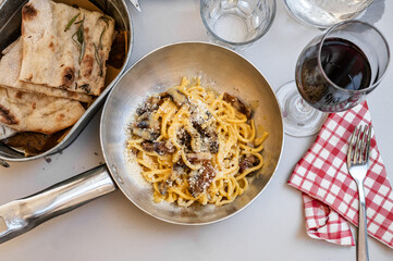Italian carbonara pasta with bread and red wine on a table