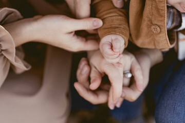 Close-up of baby hand resting on parents' hands