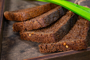 Freshly baked dark rye bread slices on a wooden board Savory vegetable pie served with fresh garnishes on a white plate