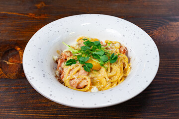 Delicious creamy pasta topped with fresh herbs served in a cozy restaurant Savory vegetable pie served with fresh garnishes on a white plate