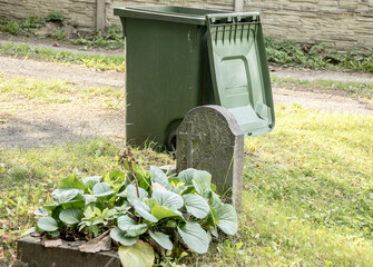 a garbage can standing next to a neglected grave, cemetery, tombstone, garbage can, neglected,...