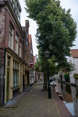 Fototapeta premium Houses with a street, a water canal and boat in the old town of Alkmaar in the Netherlands