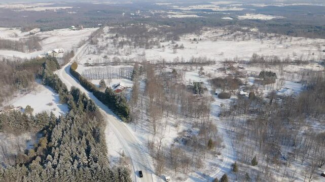 Aerial View Of A Car Driving On A Rural Road Surrounded By Forest During Winter In Canada.