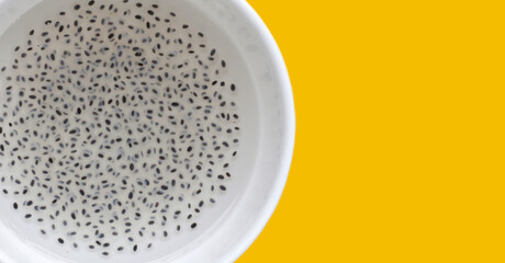 Basil seeds in syrup in bowl on yellow background.