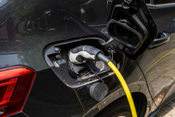 The image features an electric vehicle being charged at a modern station, highlighting the shift towards sustainable transportation and eco-conscious living in urban areas.