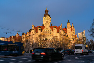 Fototapeta premium Leipzig town hall at sunset in winter. Traffic in the foreground. The last rays of sunlight illuminate the building.